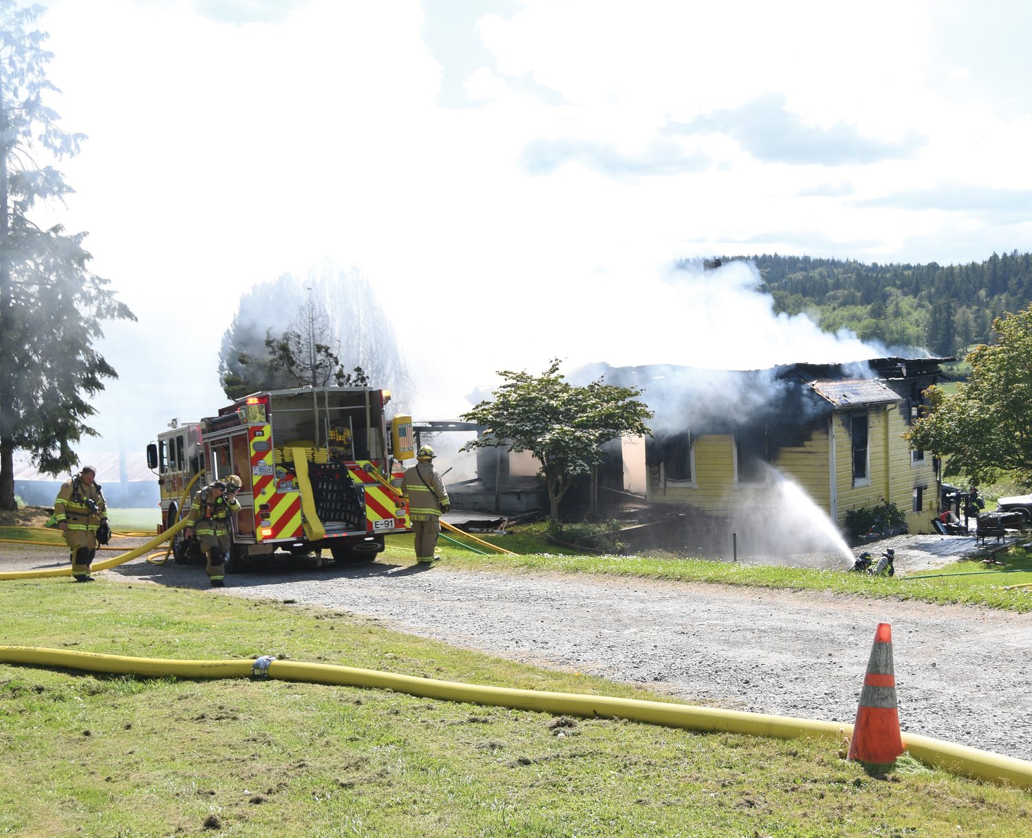 Firefighters use defensive measures to contain the fire at a Chimacum residence Thursday afternoon.
